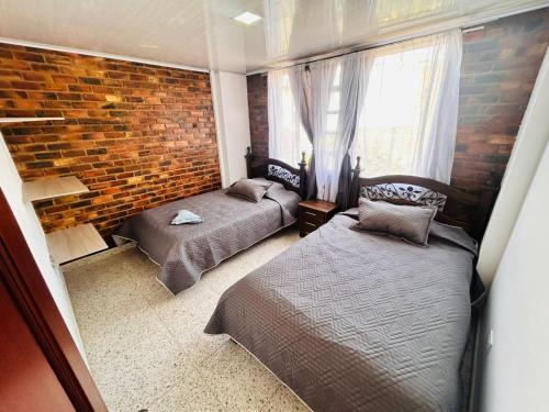 een slaapkamer met twee bedden en een bakstenen muur bij Casa Nobsa ArteSana in Nobsa