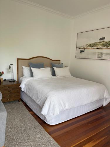 une chambre avec un grand lit avec des draps blancs dans l'établissement River Retreat, à Grays Point