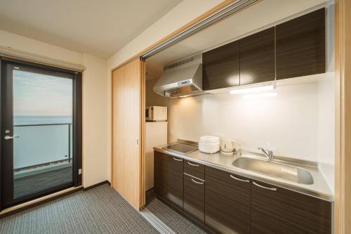 a small kitchen with a sink and a window at Apartment Hotel YAEZAKI in Beppu