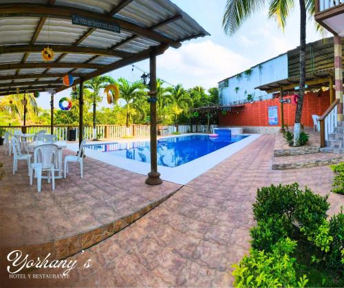 a patio with a table and chairs next to a swimming pool at Yorhanys Hotel in Puerto Barrios