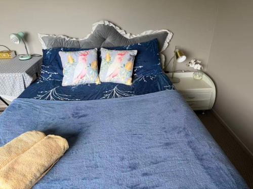 een slaapkamer met een blauw bed met blauwe lakens en kussens bij Sunny garden view suite with private bathroom in Auckland