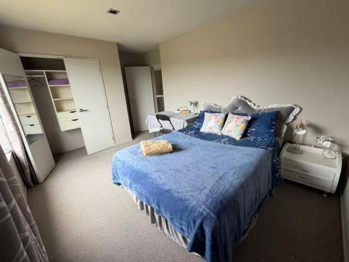 a bedroom with a bed with a blue comforter at Sunny garden view bedroom with private bathroom in Auckland