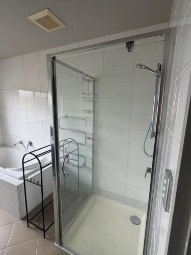 a shower with a glass door in a bathroom at Sunny garden view bedroom with private bathroom in Auckland