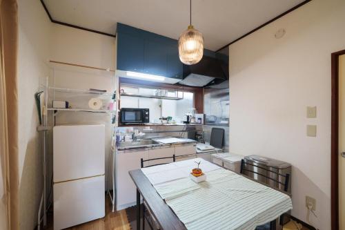 a small kitchen with a table and a refrigerator at Blue moon house miyama in Funabashi