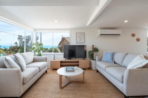 a living room with two couches and a tv at Magpie Sands - Ocean Views & Seaside Luxury - Steps to beach in Aldinga Beach