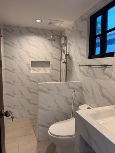 a white bathroom with a toilet and a sink at Sea La Vie Guesthouse in Pooc