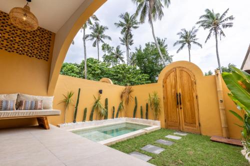 een achtertuin met een zwembad en een houten deur bij Terracota Villas in Kuta Lombok