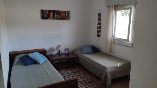 a room with two beds and a table and a window at Chalet de campo in Piriápolis