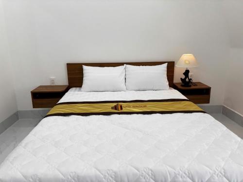 a bedroom with a large white bed with a yellow blanket at LTC Hotel in Long Thành