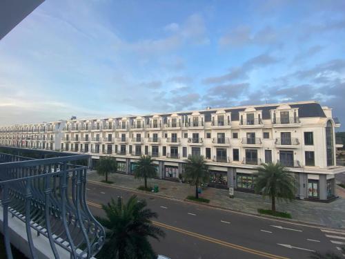 a large white building with palm trees in front of it at LTC Hotel in Long Thành