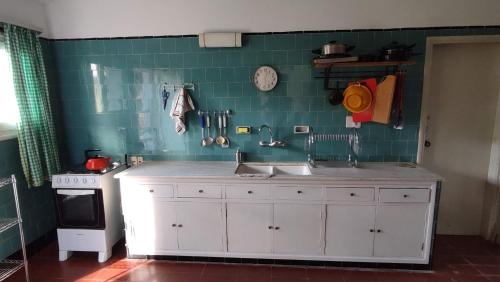 a kitchen with a sink and a green tiled wall at Chalet de campo in Piriápolis