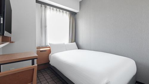 a white bed in a room with a window at Sotetsu Fresa Inn Kobe Sannomiya in Kobe