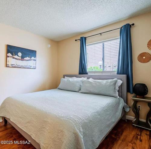 ein Schlafzimmer mit einem Bett mit blauen Vorhängen und einem Fenster in der Unterkunft Copper Star Condominiums in Tucson