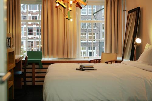 een slaapkamer met een bed en een groot raam bij Rosalia's Menagerie Cocktail bar & InnUpstairs in Amsterdam