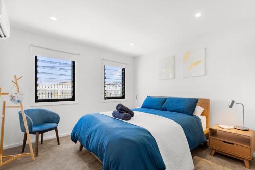 a bedroom with two beds and a chair at Bellagio - Swimming Pool with Ocean Views in Callala Beach