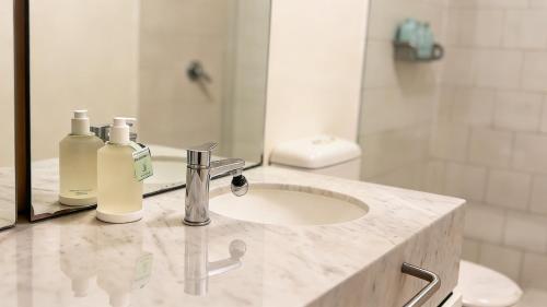 a bathroom sink with two bottles of soap and a mirror at Spacious landmark in the heart of CBD in Melbourne