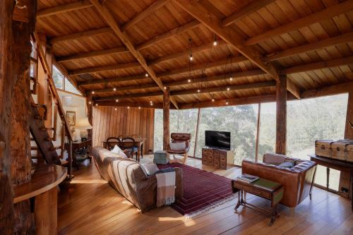 a living room with couches and chairs in a cabin at Wilderness Retreat 15mins to CBD, bath tub, forest views in Ridgeway
