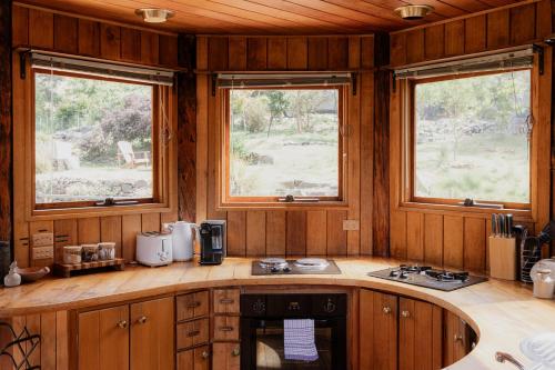 a kitchen with wooden cabinets and two windows at Wilderness Retreat 15mins to CBD, bath tub, forest views in Ridgeway