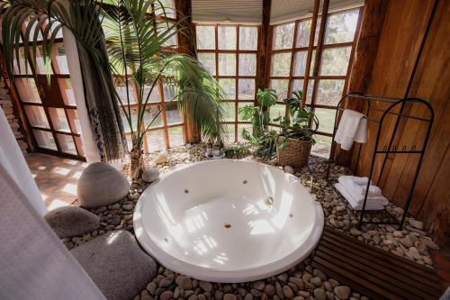 a bath tub in a room with rocks and plants at Wilderness Retreat 15mins to CBD, bath tub, forest views in Ridgeway