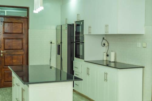 a kitchen with white cabinets and a black counter top at Grato Pacho in Kisumu