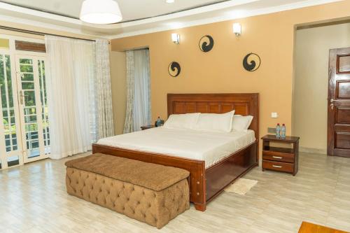 a large bedroom with a bed and a ottoman in it at Grato Pacho in Kisumu