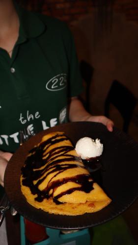 a person holding a plate with a dessert on it at CatBa Pod Hostel & Rooftop Bar in Cat Ba