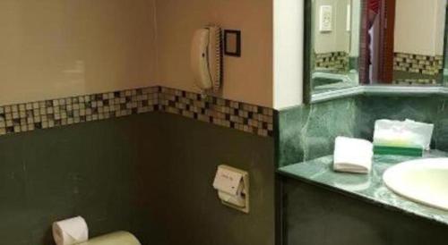 een badkamer met een wastafel, een toilet en een spiegel bij The CentrePoint Hotel in Kampong Kiulap