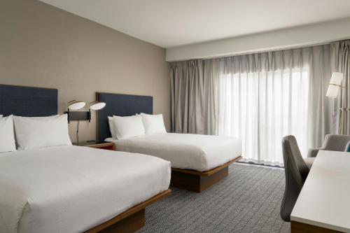 a hotel room with two beds and a chair at Courtyard Brunswick in Brunswick