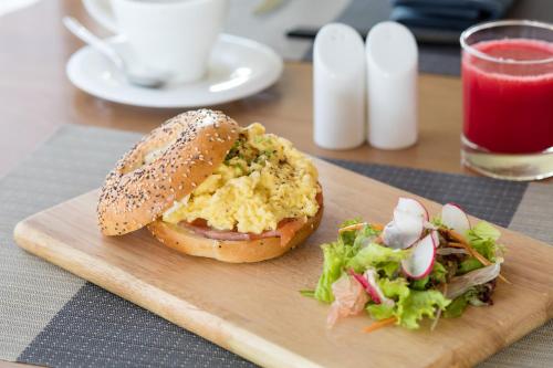 a sandwich and a salad on a wooden cutting board at Fusion Suites Saigon in Ho Chi Minh City