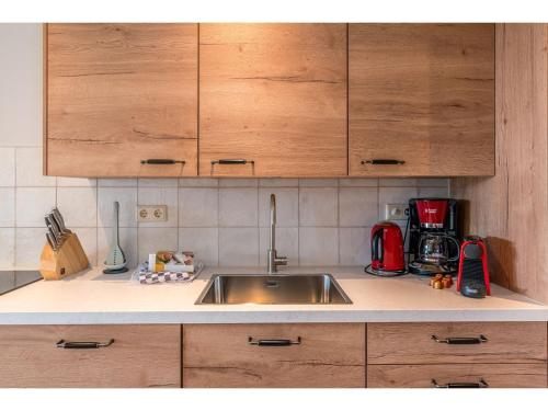 a kitchen counter with a sink and wooden cabinets at Lovely Holiday Home in Texel near Sea in Oost