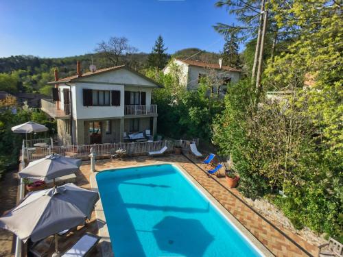 een uitzicht over een zwembad met parasols en een huis bij Huge Holiday Home in Marina di Castagneto Carducci near Sea in Donoratico