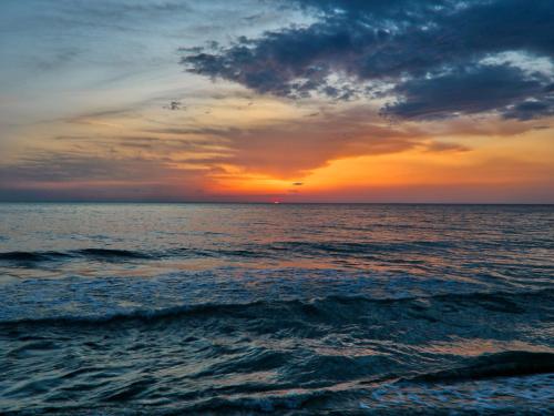 een zonsondergang boven de oceaan met een bewolkte hemel bij Huge Holiday Home in Marina di Castagneto Carducci near Sea in Donoratico