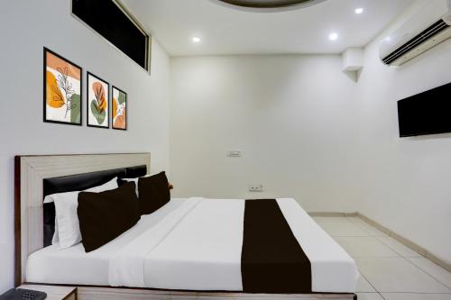 een slaapkamer met een groot wit bed met zwarte kussens bij Hotel O Lohgarh Road Zirakpur Formerly JB Plaza in Zirakpur
