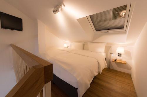 a small bedroom with a white bed and a television at Downtown Vi Vadi Hotel in Munich