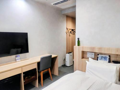 a hotel room with a desk with a tv and a bed at New Grand Hotel in Shinjo