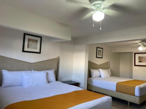 a hotel room with two beds and a ceiling fan at Hotel La Sexta in Tijuana