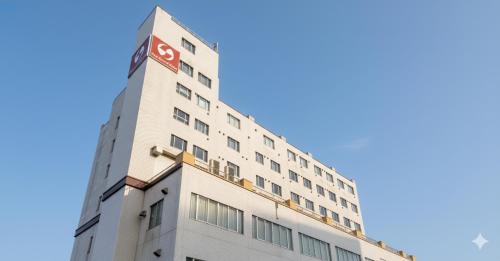 a white building with a red sign on it at New Grand Hotel in Shinjo