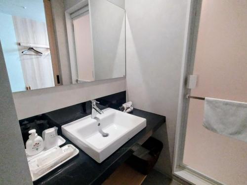 een badkamer met een witte wastafel en een spiegel bij New Grand Hotel in Shinjo