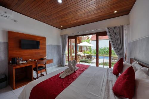 a bedroom with a bed with a desk and a television at Lavanya Villa in Nusa Penida