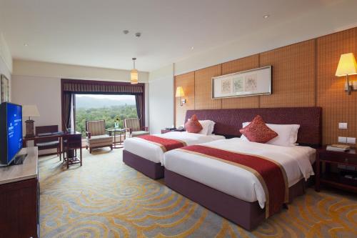 a hotel room with two beds and a television at Howard Johnson Conference Resort Chengdu in Dujiangyan