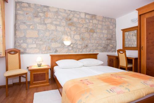 a bedroom with a bed and a stone wall at Apartments Residence Astoria in Rab