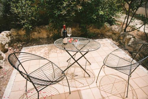 a glass table with two chairs and a bottle of wine at Smadar Inn in Zikhron Ya‘aqov