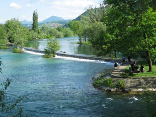 a river with a group of people sitting next to it at Apartment Beha in Bihać
