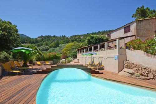 una piscina en una terraza con sillas y un edificio en Bungalows Du Maquis en Porto Vecchio