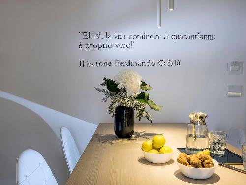 a table with two bowls of fruit and a vase of flowers at Duomo Suites & Spa in Catania