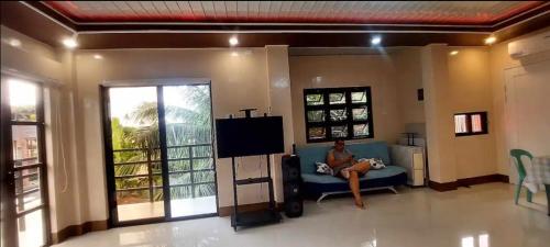 a woman sitting on a couch in a living room at Casa Ginhawa Ozamiz in Ozamis