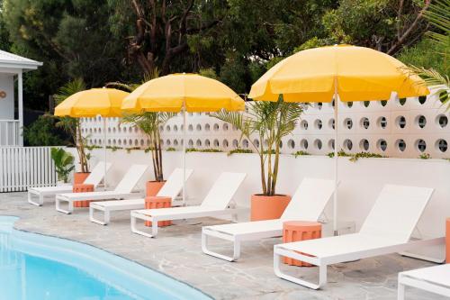 een rij stoelen met parasols naast een zwembad bij Sunnymead Hotel in Aireys Inlet