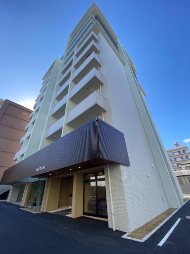a tall white building with a black awning at Apartment Hotel YAEZAKI in Beppu