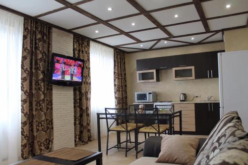 a living room with a couch and a kitchen with a television at Apartments on Chkalova in Maykop