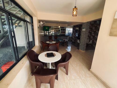 ein Esszimmer mit Tischen, Stühlen und Fenstern in der Unterkunft A Oasis Taveta in Taveta